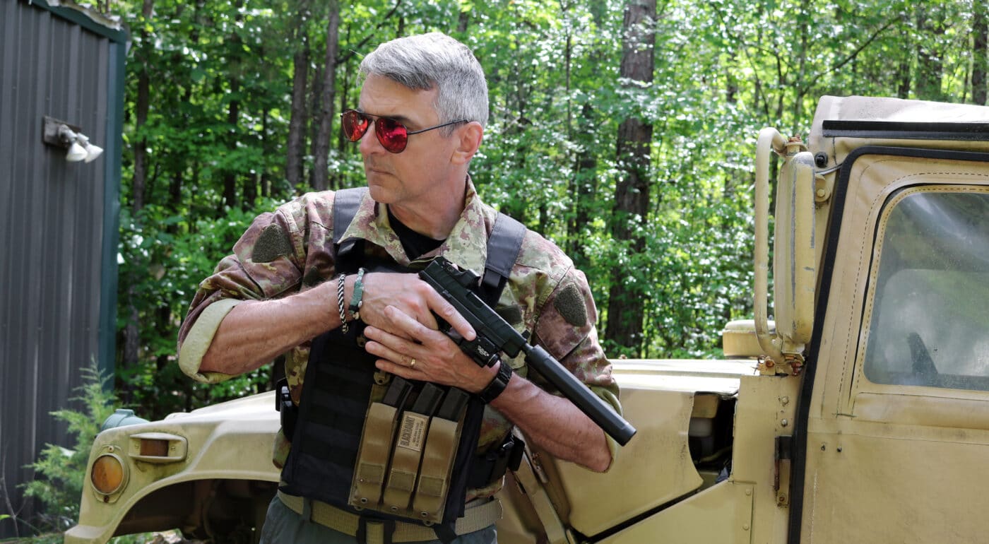 Man holding Springfield XD-M Elite pistol with SureFire suppressor