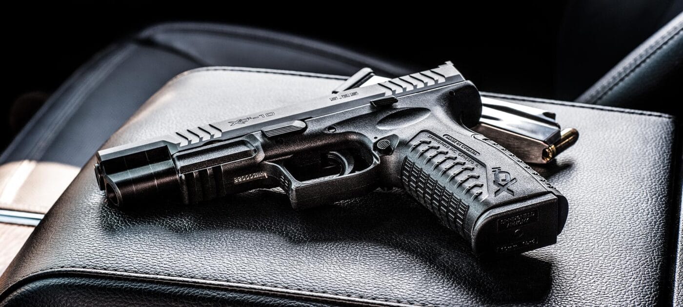 Springfield Armory XD-M 10mm pistol sitting on center console of vehicle