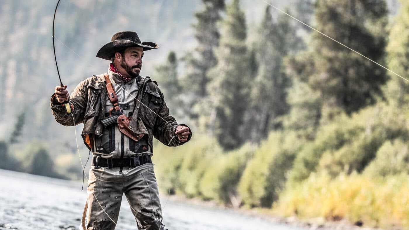 Man fly fishing while carrying a 1911 TRP in a leather chest rig