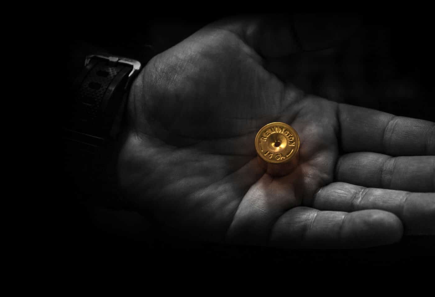 Person's hand holding part of a Remington shotgun shell