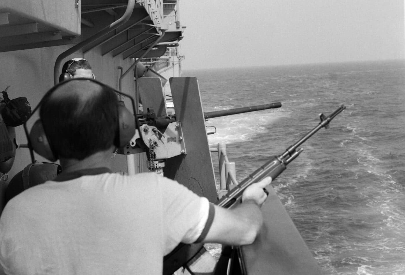 USN sailor holds an M14 rifle as another crewman mans an M2 .50-caliber machine gun during a general quarters drill