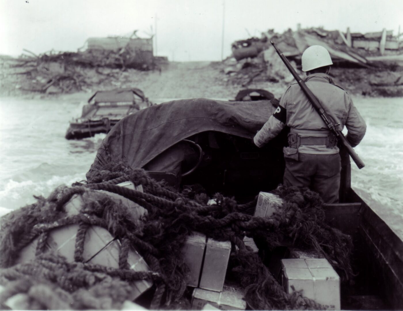 An M1903A3-armed MP guards supplies aboard a DUKW amphibian coming ashore at Le Havre, France during February 1945