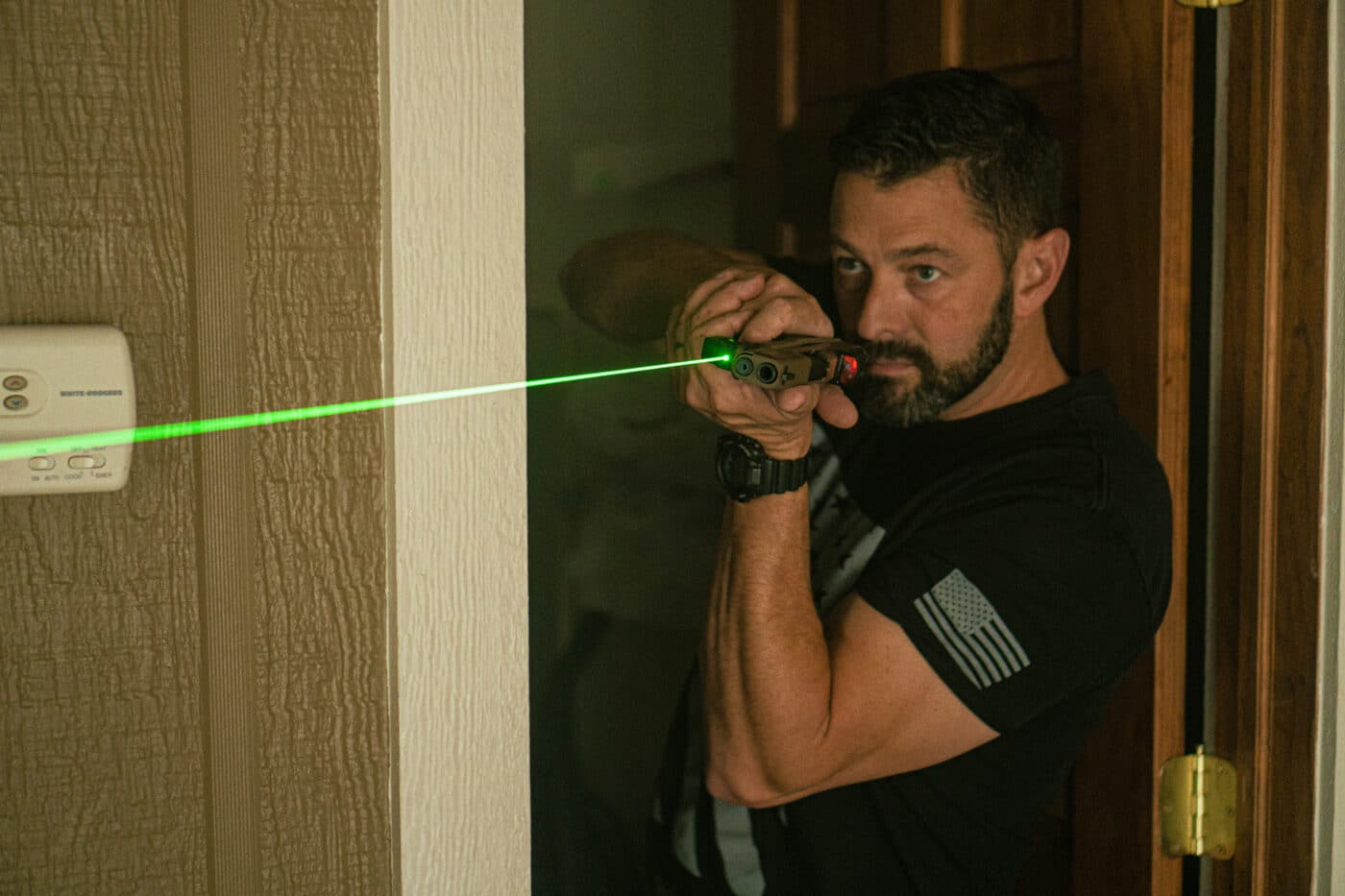 Man using a pistol with a laser during home defense