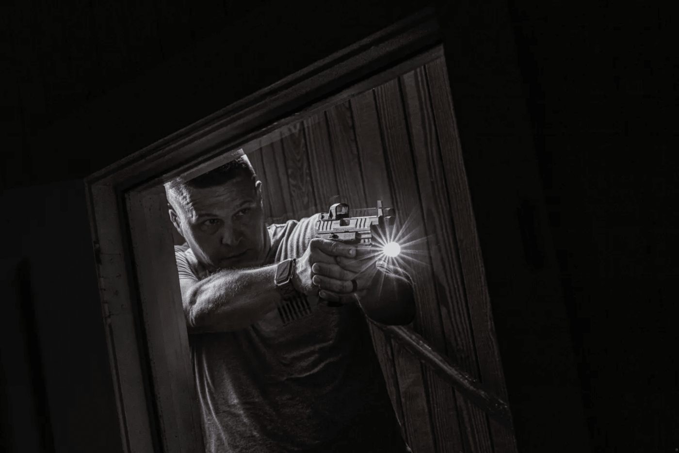 Man using a pistol with light in low light shooting situation