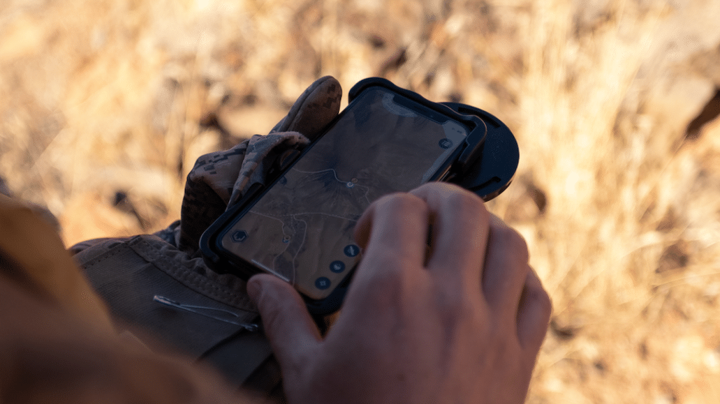 Person holding smartphone with Scout To Hunt app