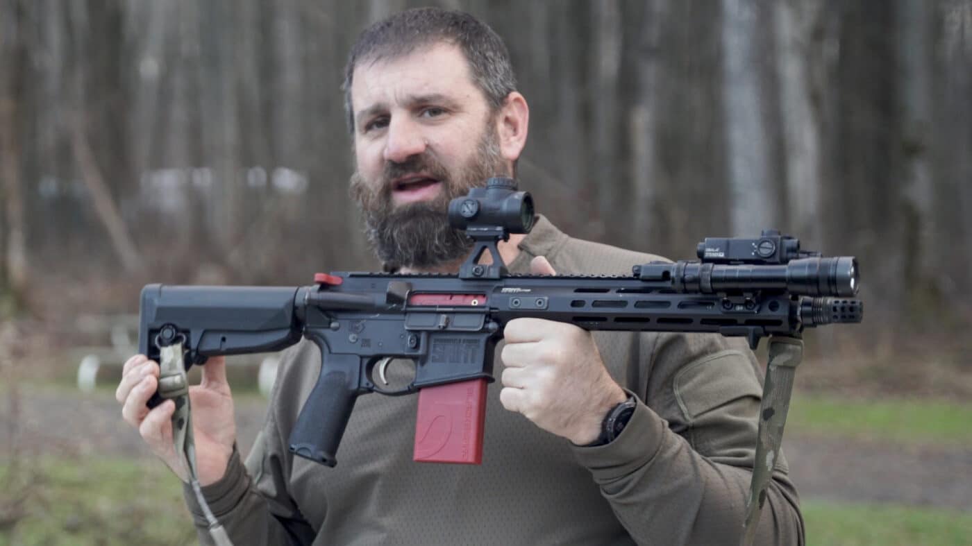 Man holding AR with automatic trigger reset training system