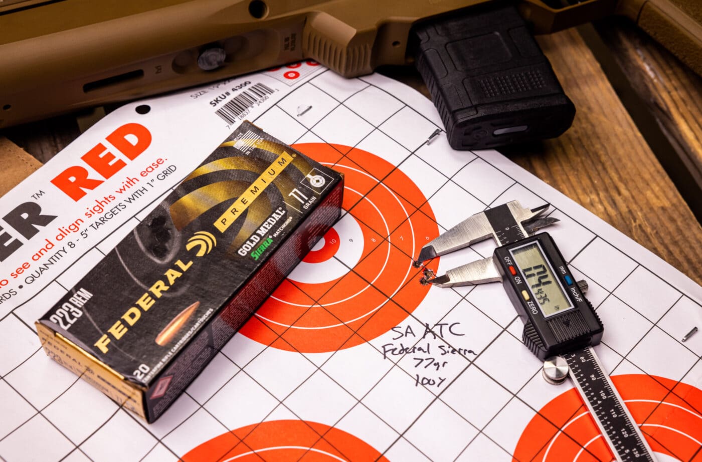 Target measuring tool next to ammo and rifle