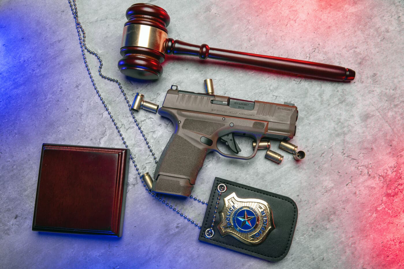 Self defense pistol next to wallet, police badge, and gavel