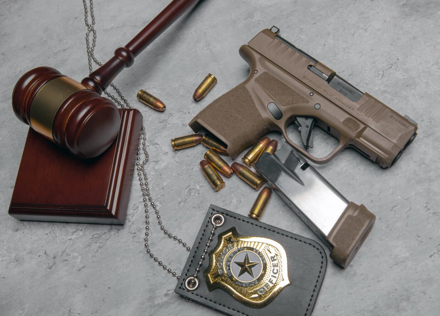 Hellcat pistol next to magazine, ammo, gavel, and police badge