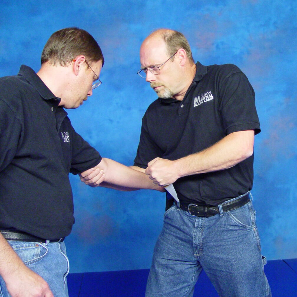 Man demonstrating using a fixed blade knife for self defense