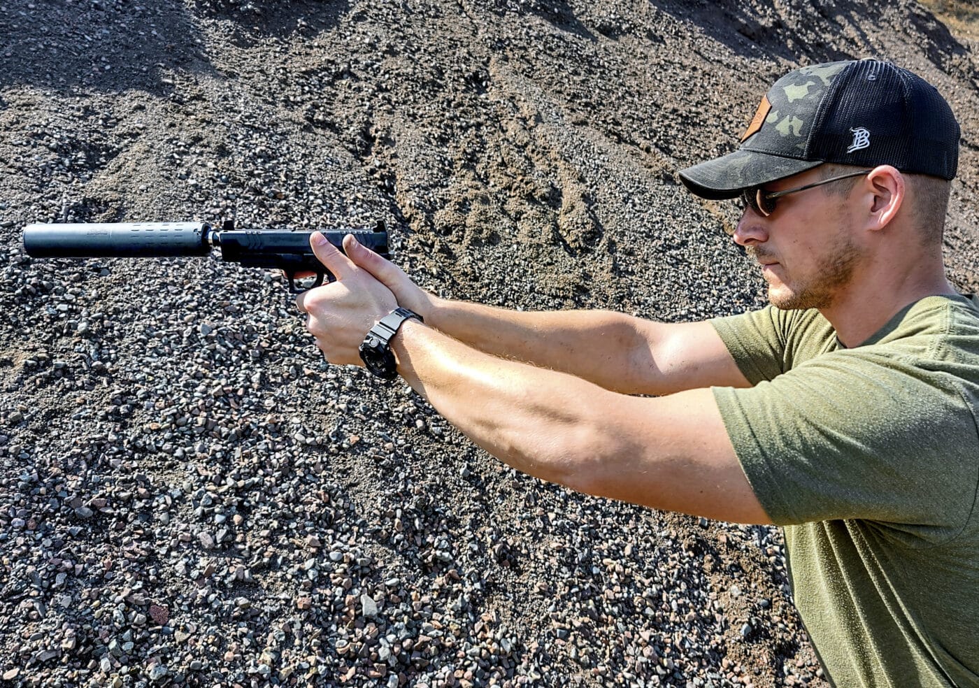 Man shooting an XD-M pistol with a SilencerCo suppressor