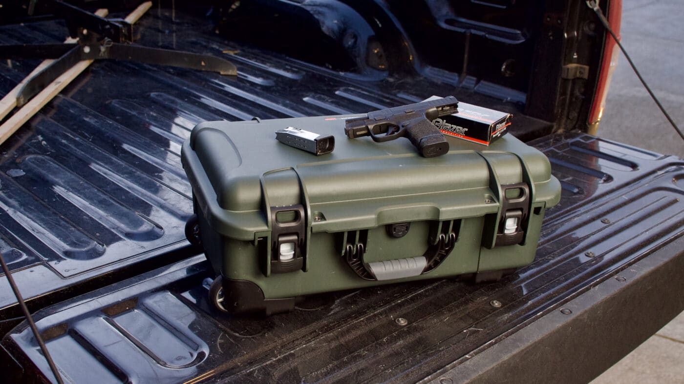 Nanuk 935 gun case in the bed of a pickup truck with pistol and ammo on top of the case