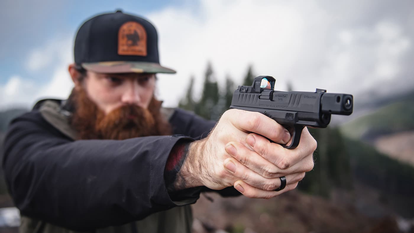 Man shooting Springfield pistol with a red dot sight mounted on the slide