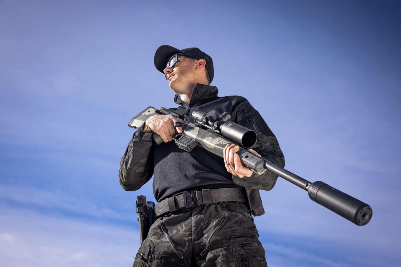 Man in hat holding Waypoint rifle with silencer mounted