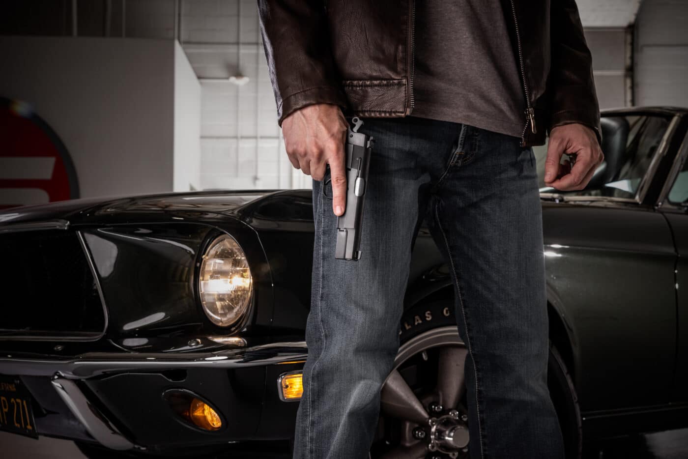 Man holding Springfield SA-35 pistol in front of a 1968 Ford Mustang