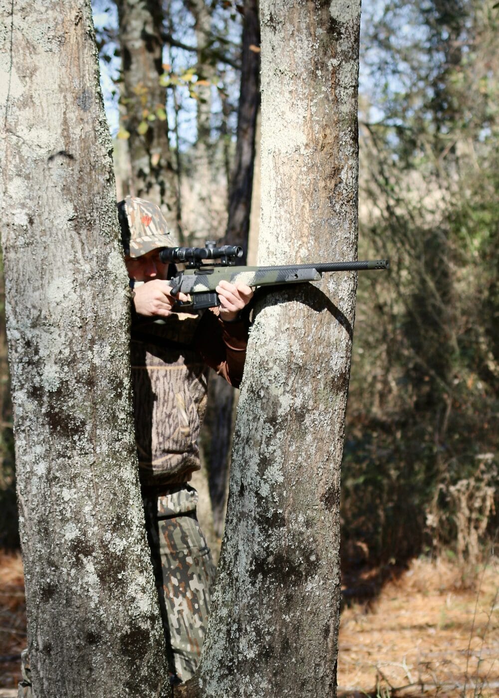 Deer hunter using a tree for a brace