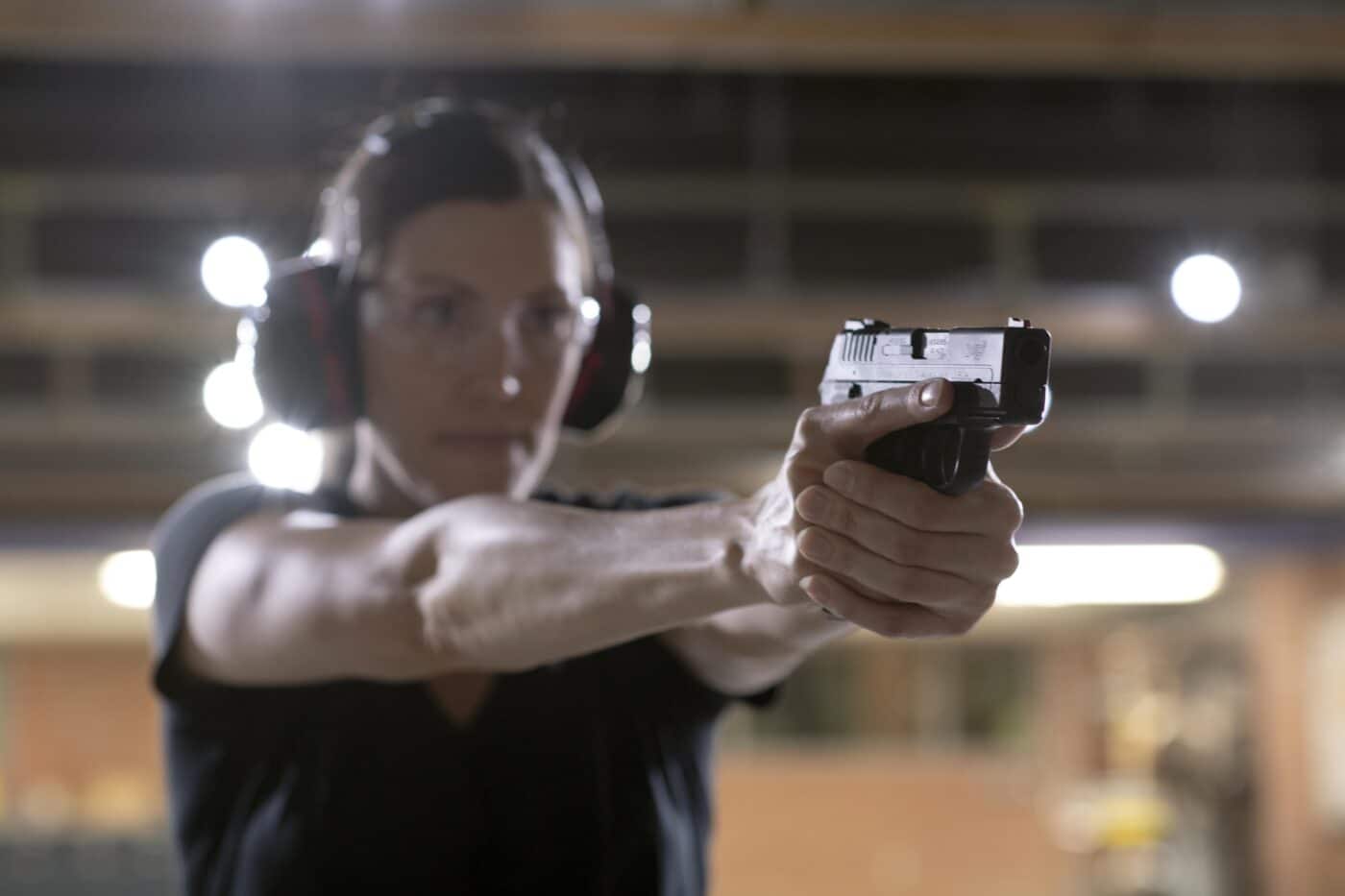 Woman shooting pistol at indoor gun range