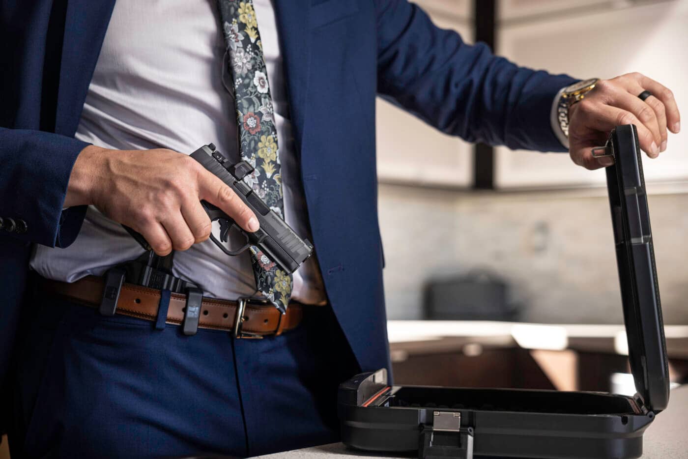 Man in suit holding Springfield Armory Hellcat Pro next to gun case