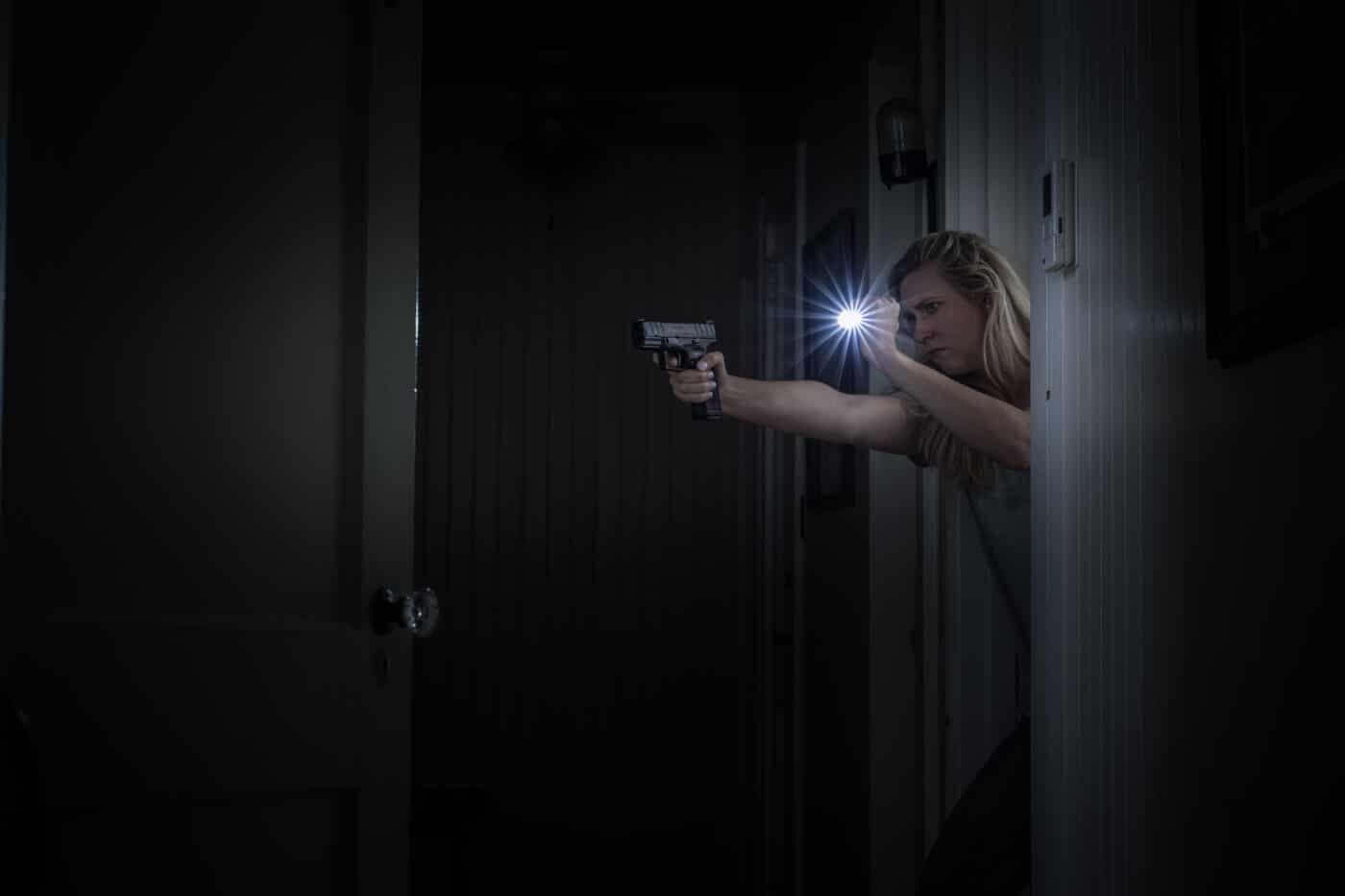Woman searching a building with pistol drawn and while carrying a handheld light