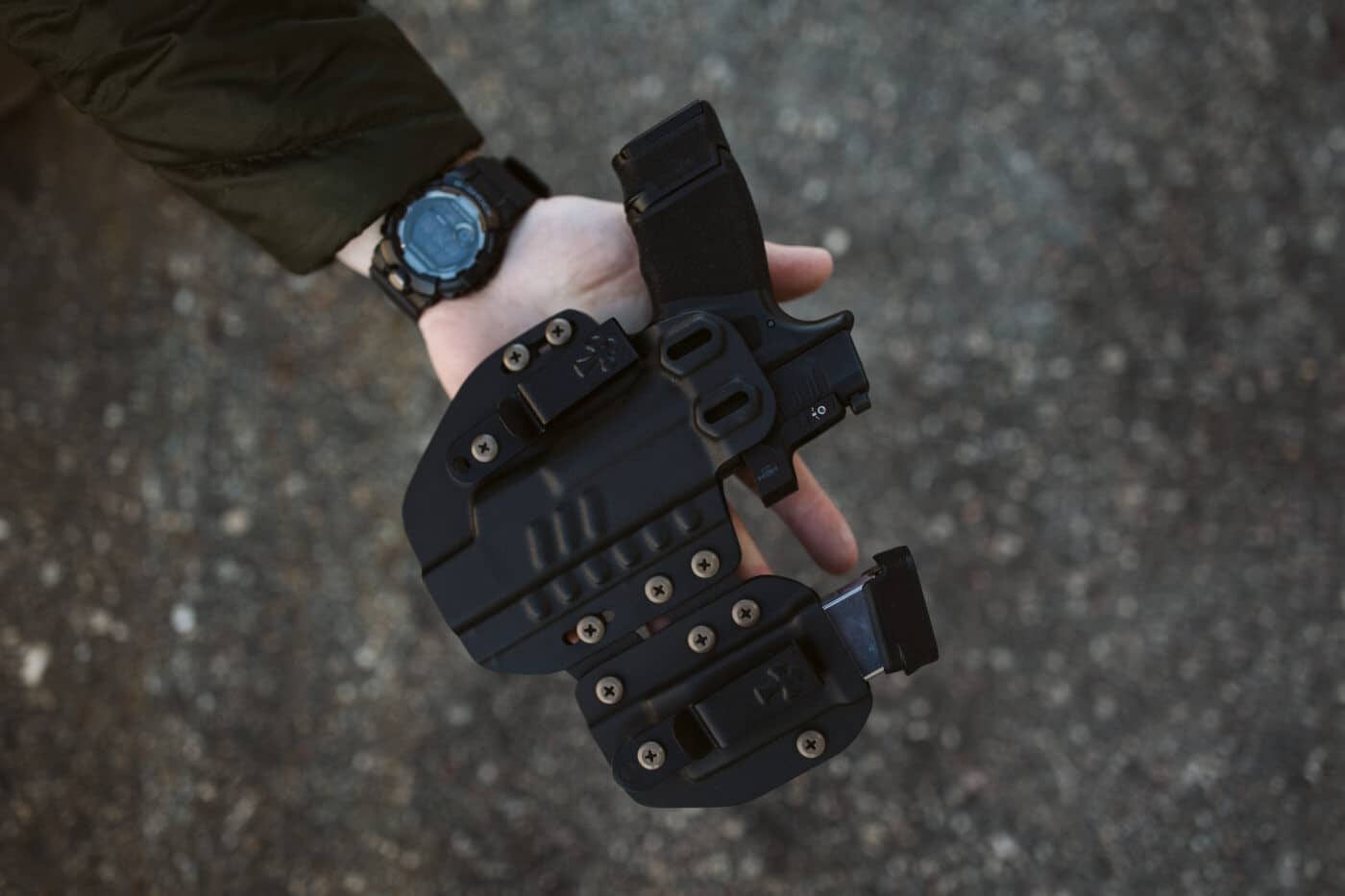 Man holding CrossBreed Rogue System holster with pistol and magazine inside