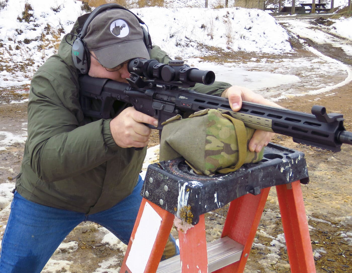 Man shooting SAINT Victor rifle off a ladder