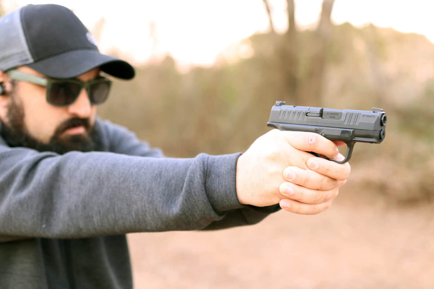 Man shooting a Hellcat pistol with iron sights