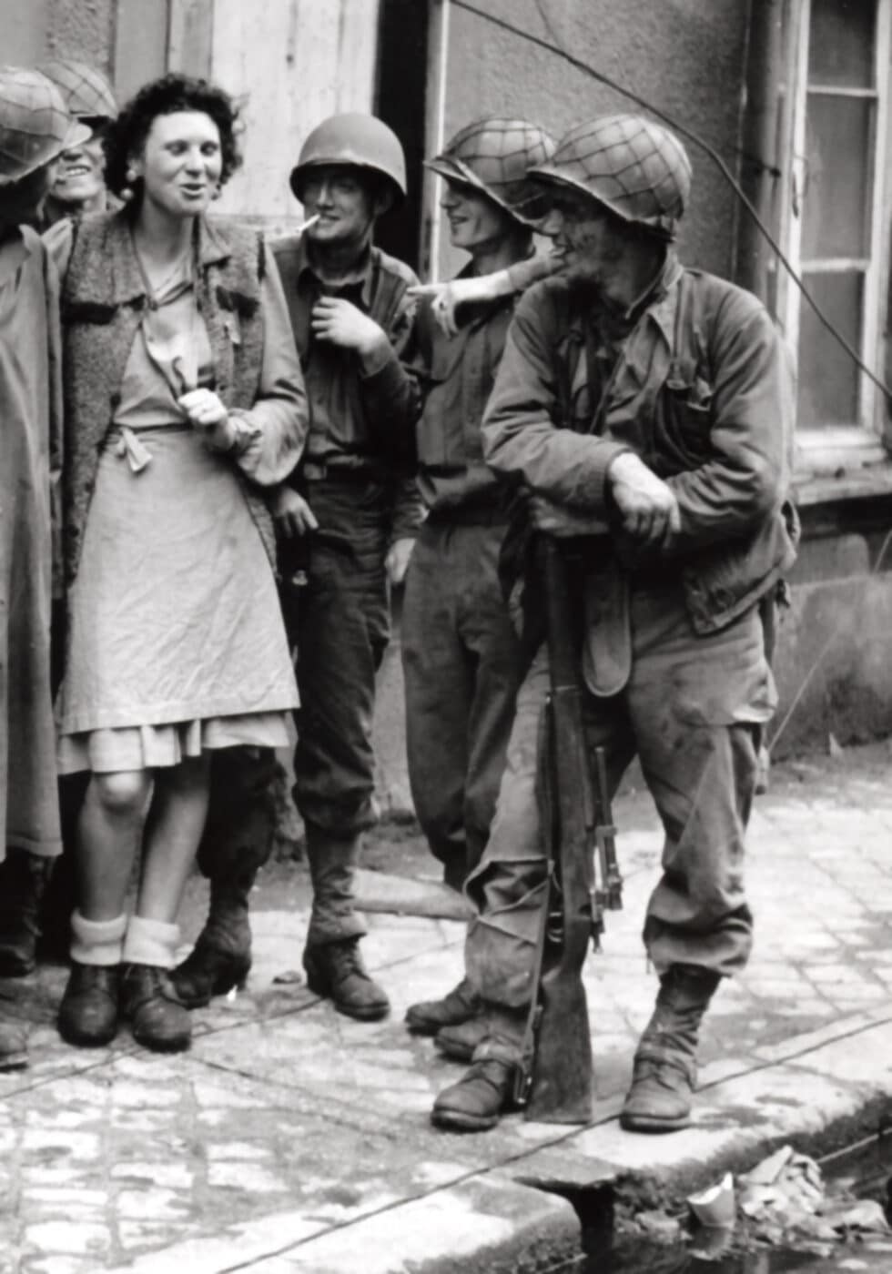 Soldier with Springfield sniper rifle talking with a woman and other soldiers in Cherbourg in June 1944