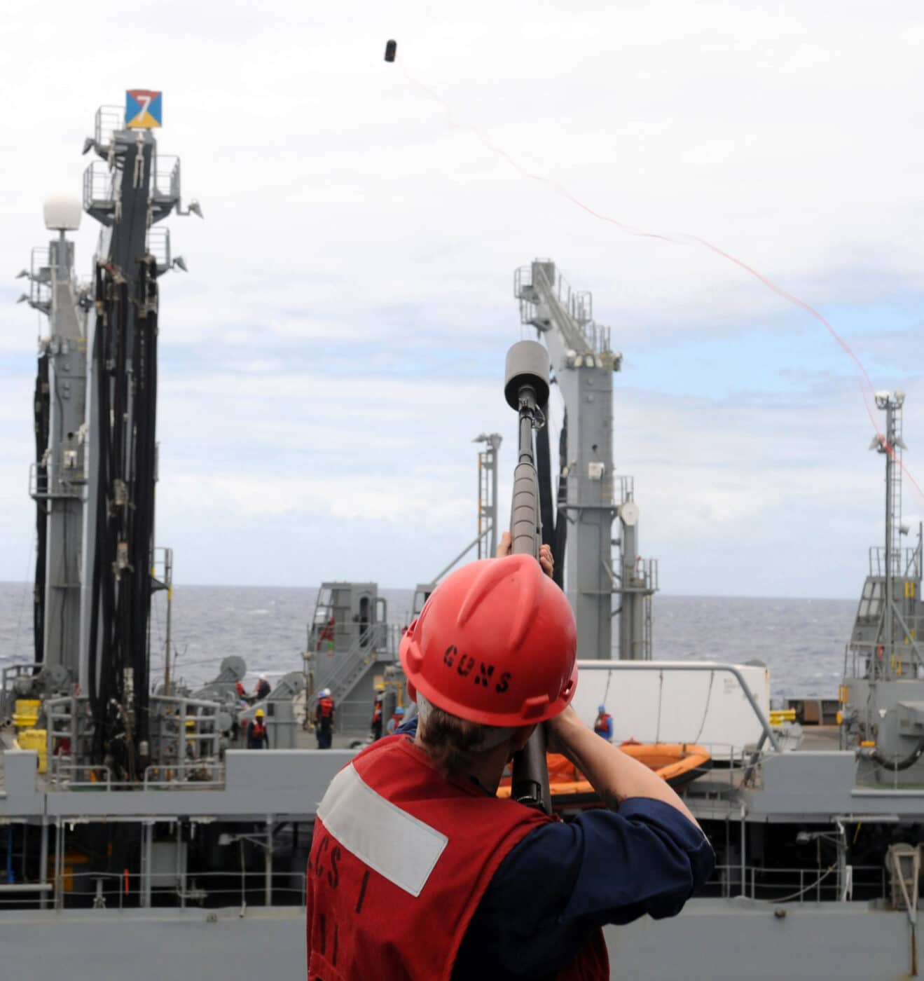 Sailor on the USS Freedom fires shot line to replenishment oiler USNS Guada
