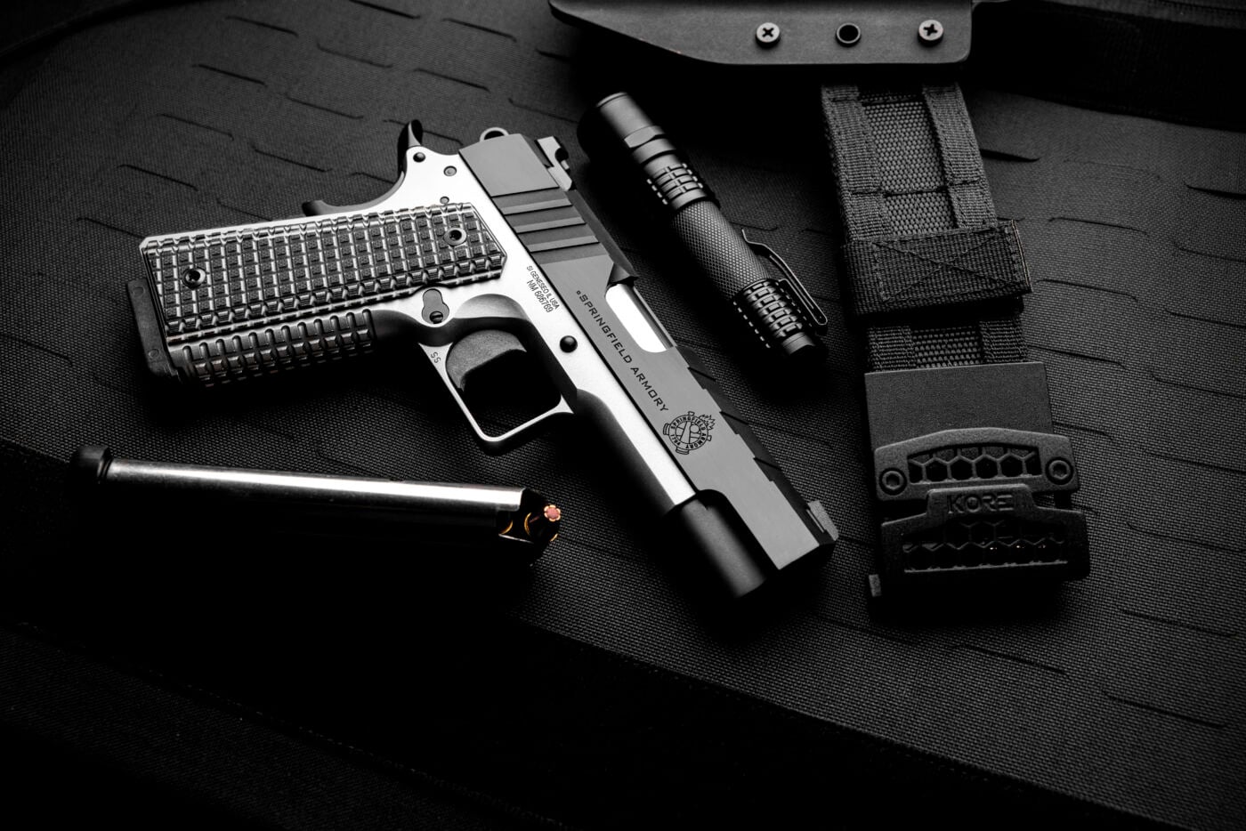Springfield Emissary 9mm pistol next to loaded magazine and flashlight