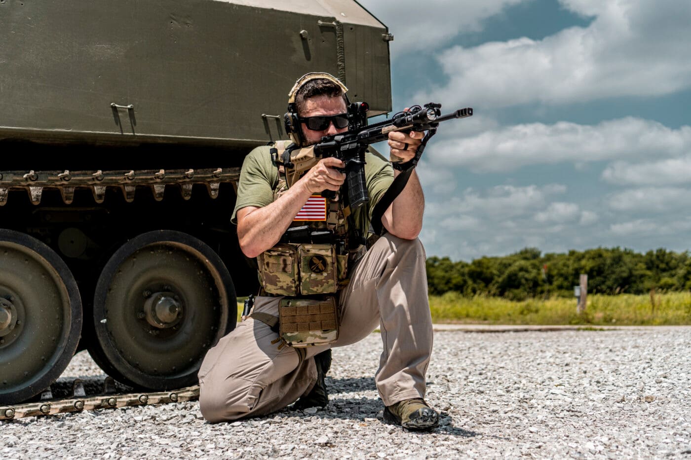 Man shooting rifle while carrying a plate carrier with battle belt setup