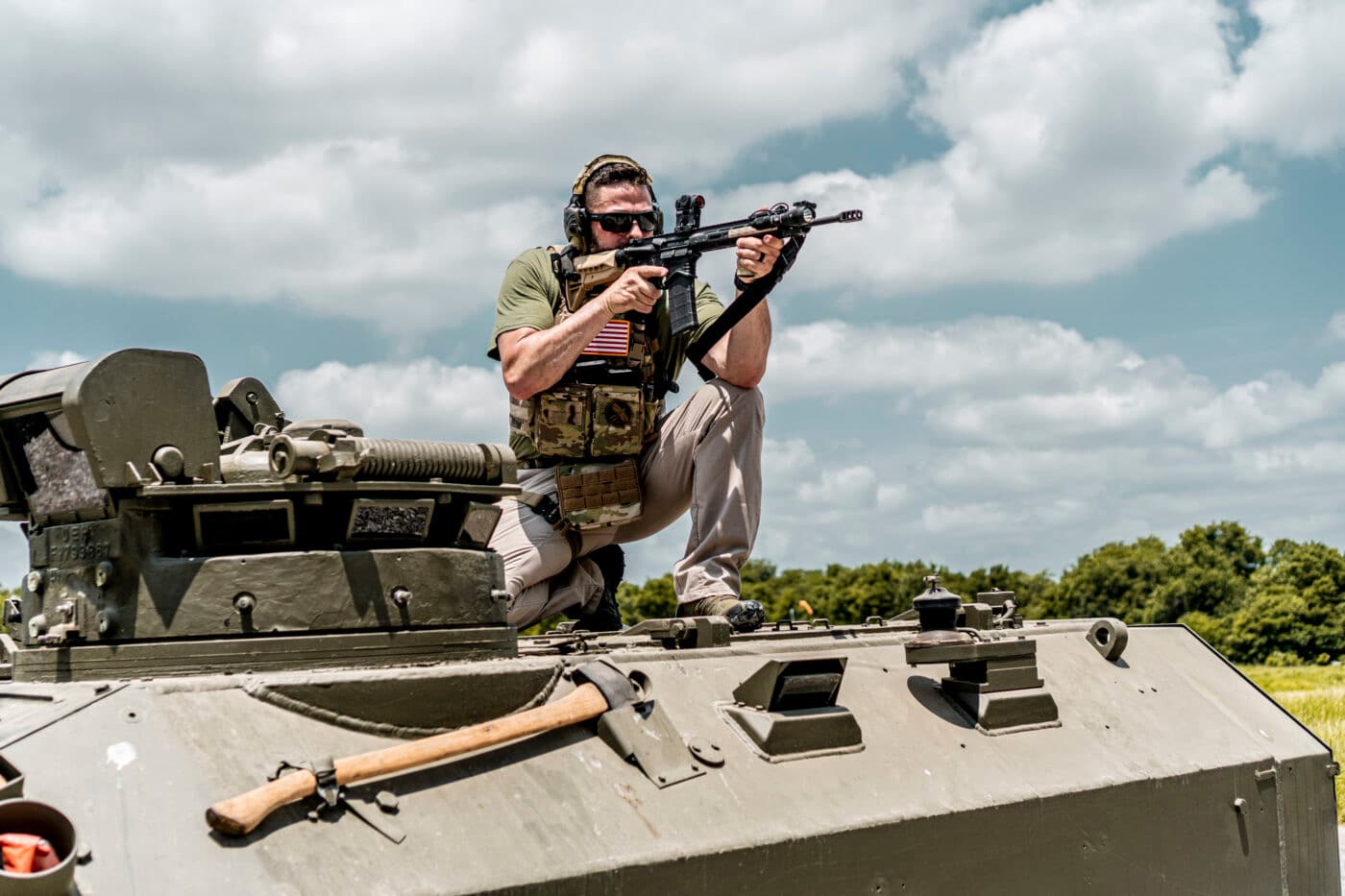 Man with body armory shooting AR rifle from APC