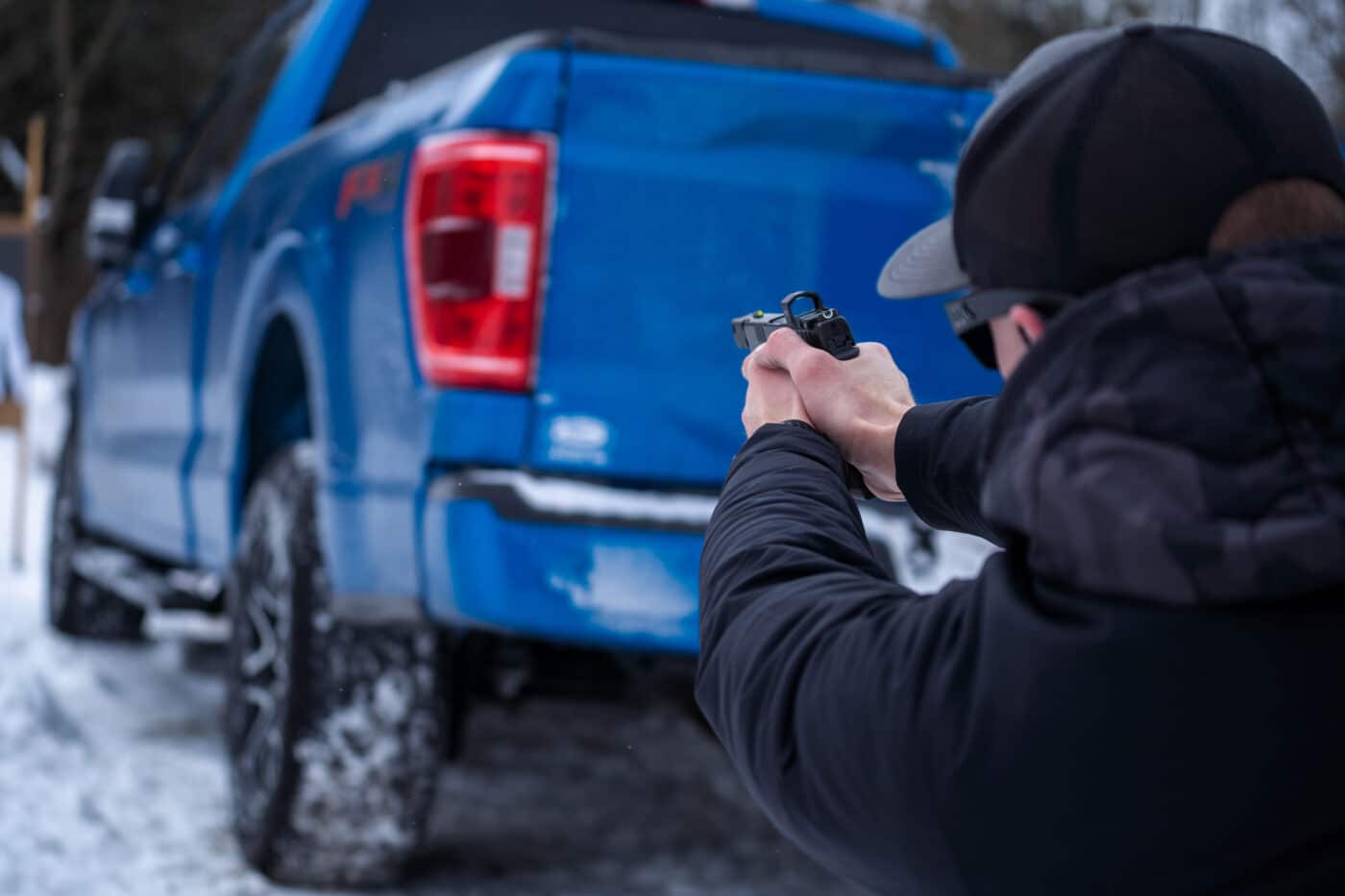 Man shooting a target from behind a truck