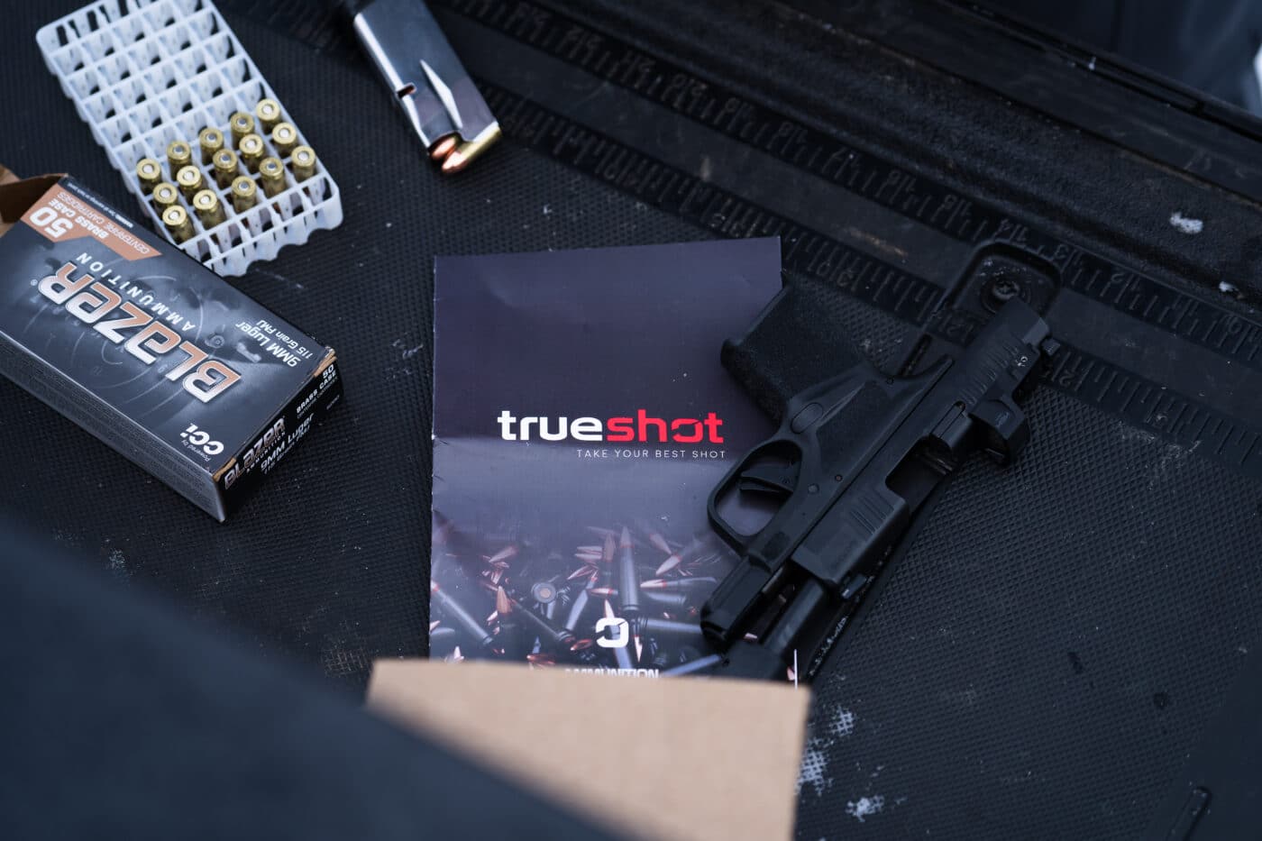 True Shot Gun Club pamphlet next to pistol and ammo