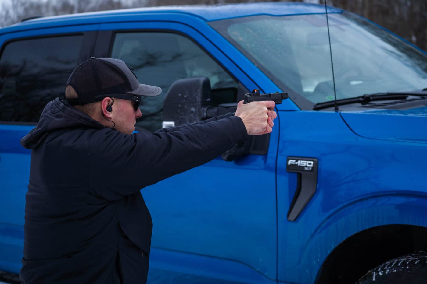 Man demonstrating which parts of a car are best for stopping bullets