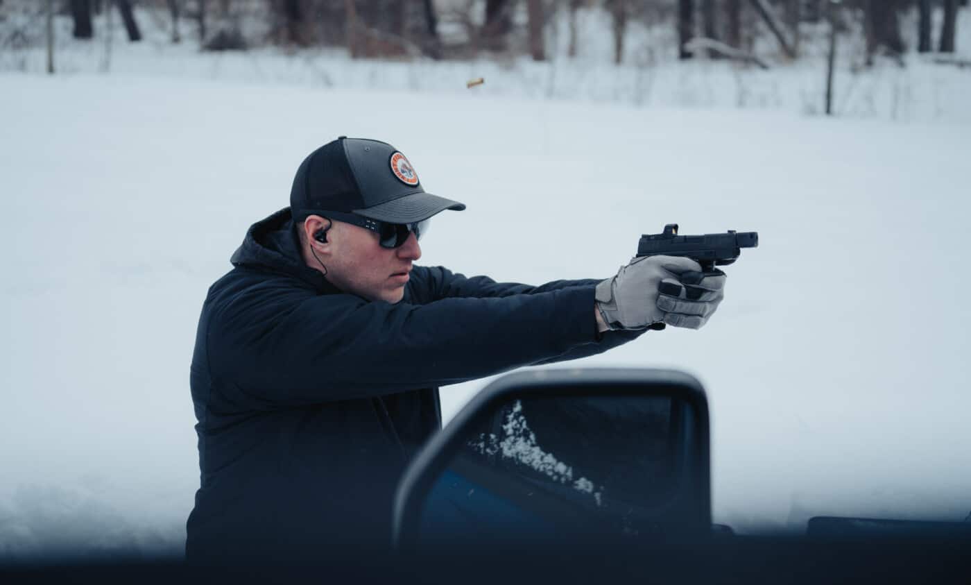 Man standing back from cover to work the angles on the shooting range in the snow.