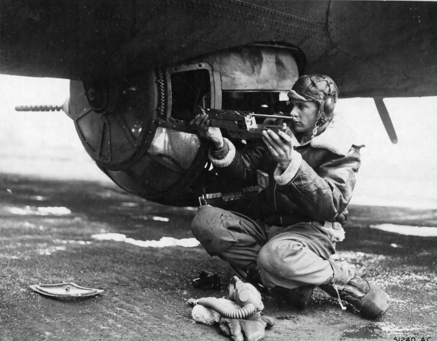 A ball turret gunner of the 8th Air Force removes his AN/M2 .50 cal MG for cleaning during World War II