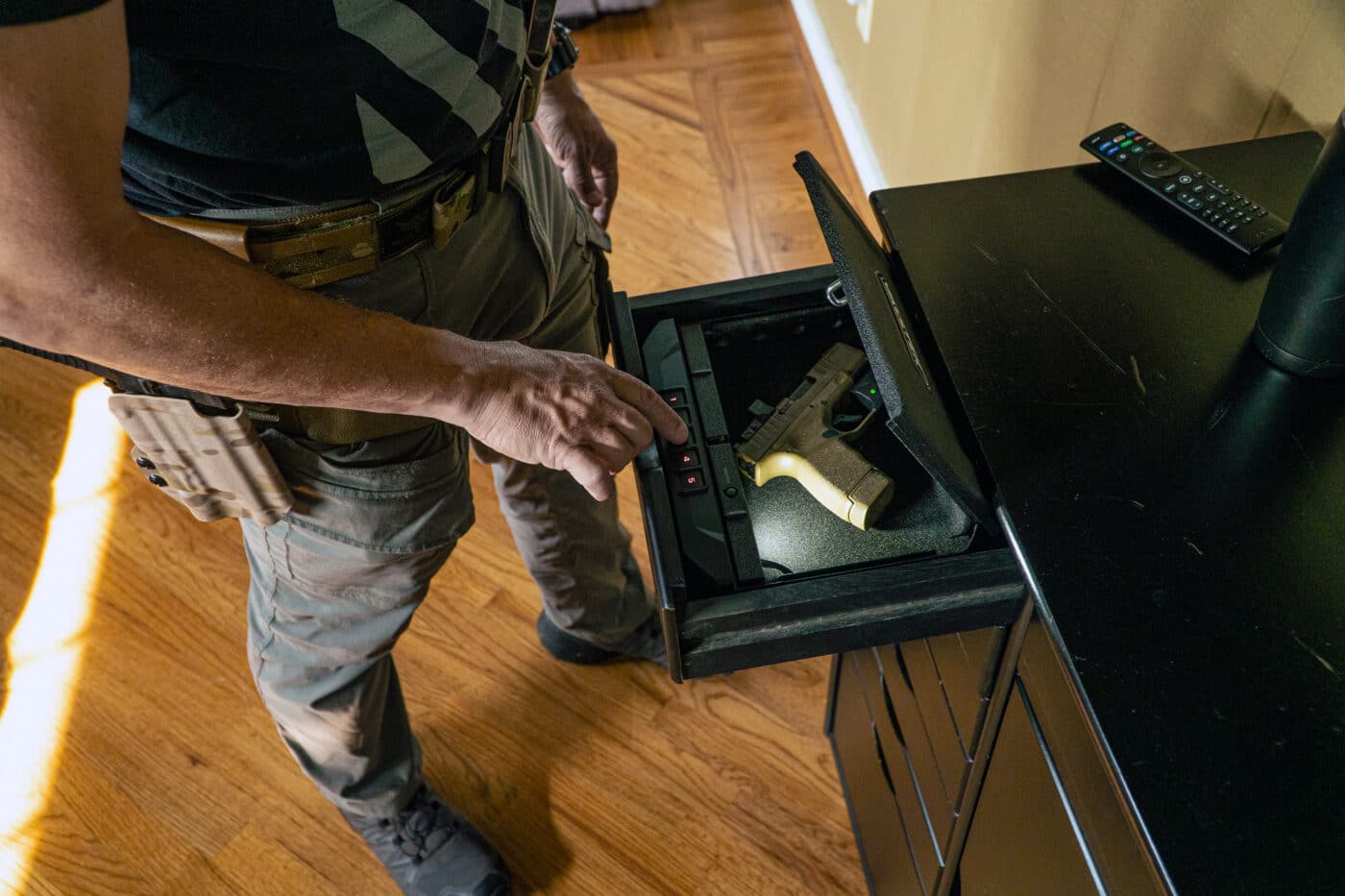Man putting a pistol in a safe inside a drawer