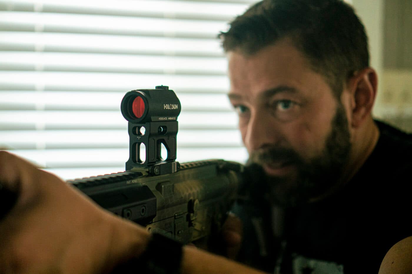 Man with red dot sight mounted on home defense rifle