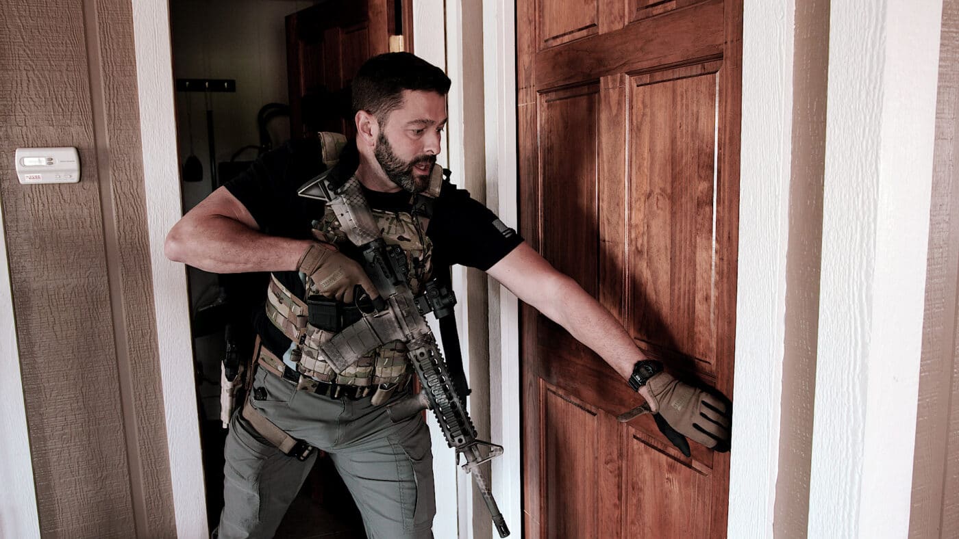 Man about to open a pocket door while clearing a house