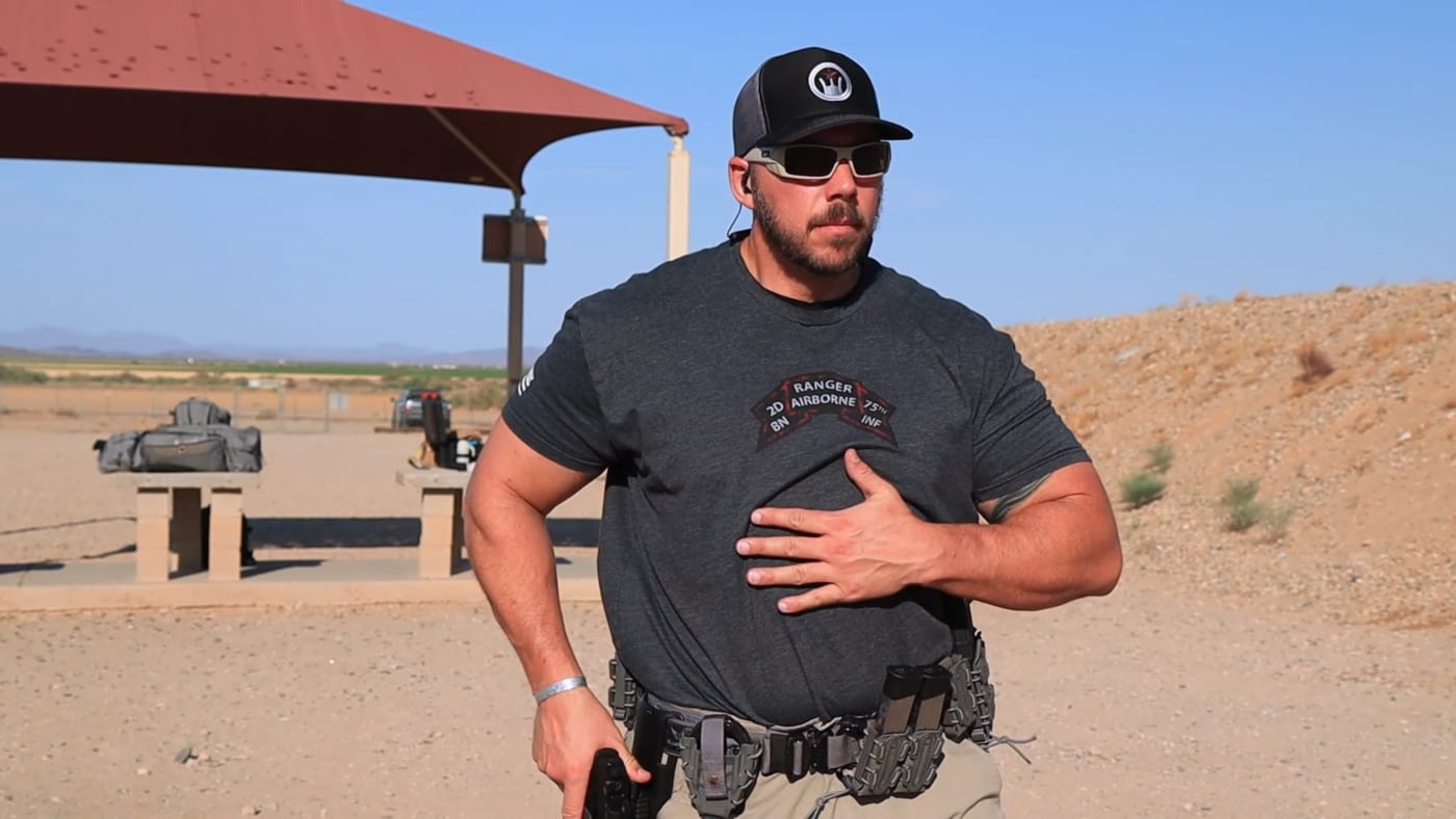 Man at a range demonstrating pistol draw from holster