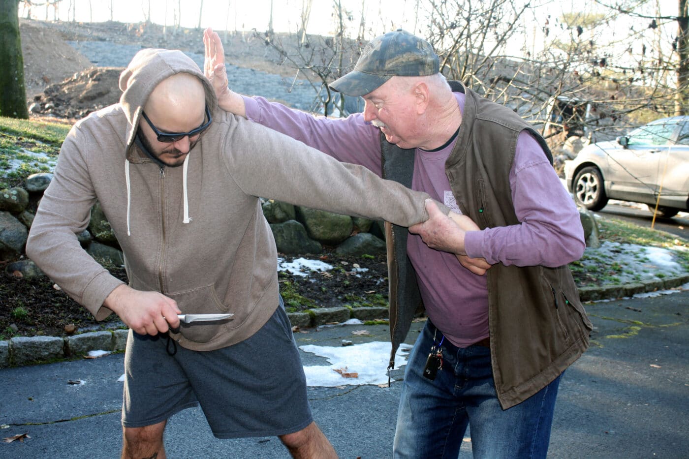 Man demonstrating a knife attack against another man carrying concealed