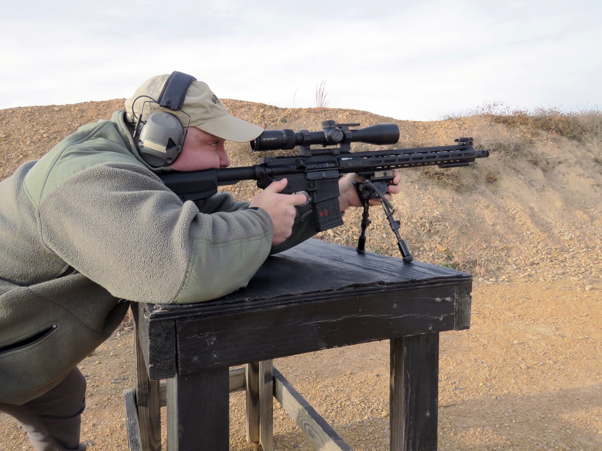 Man shooting SAINT AR-15 from bench with bipod