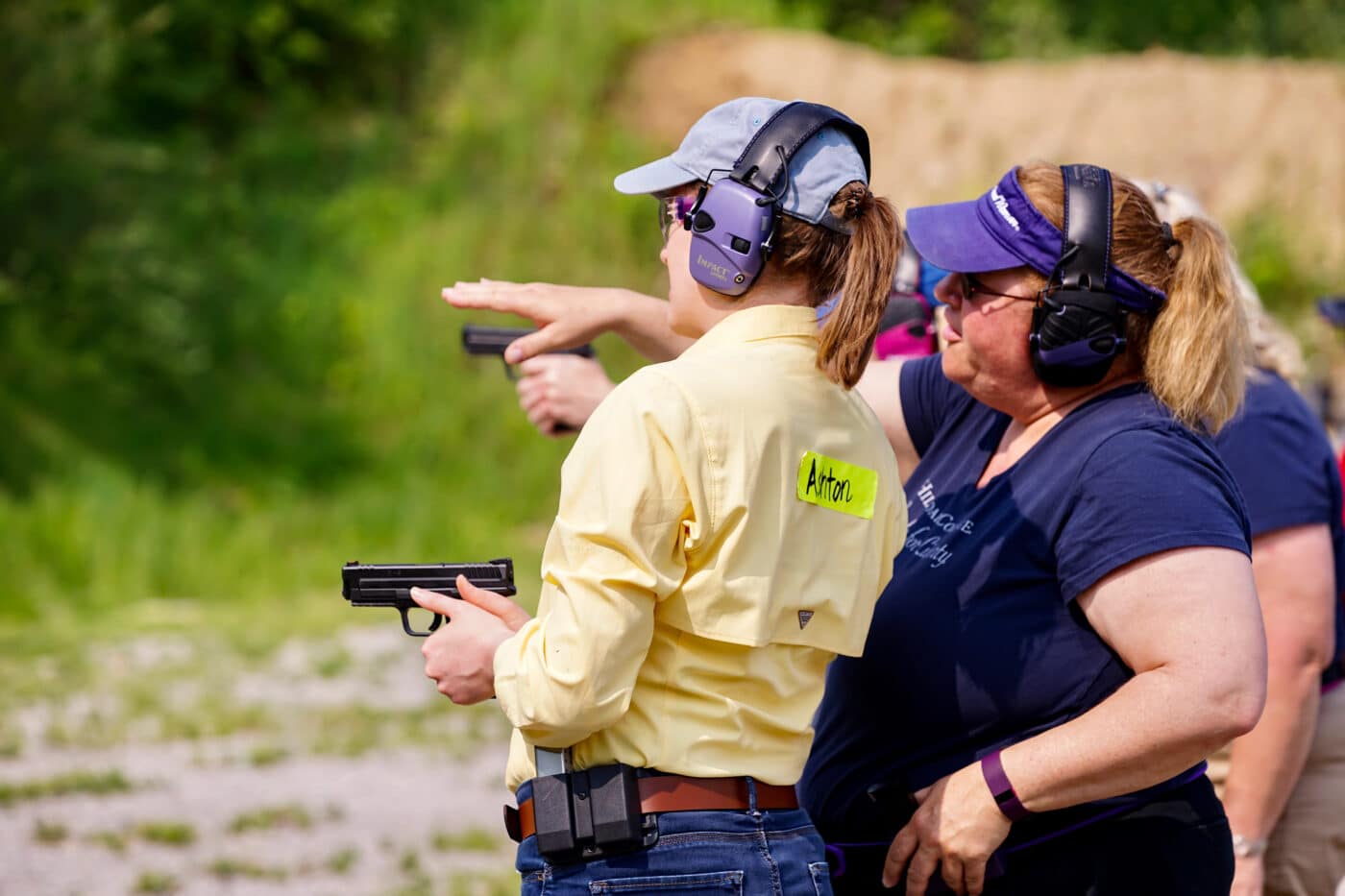 Woman holding pistol while instructor trains