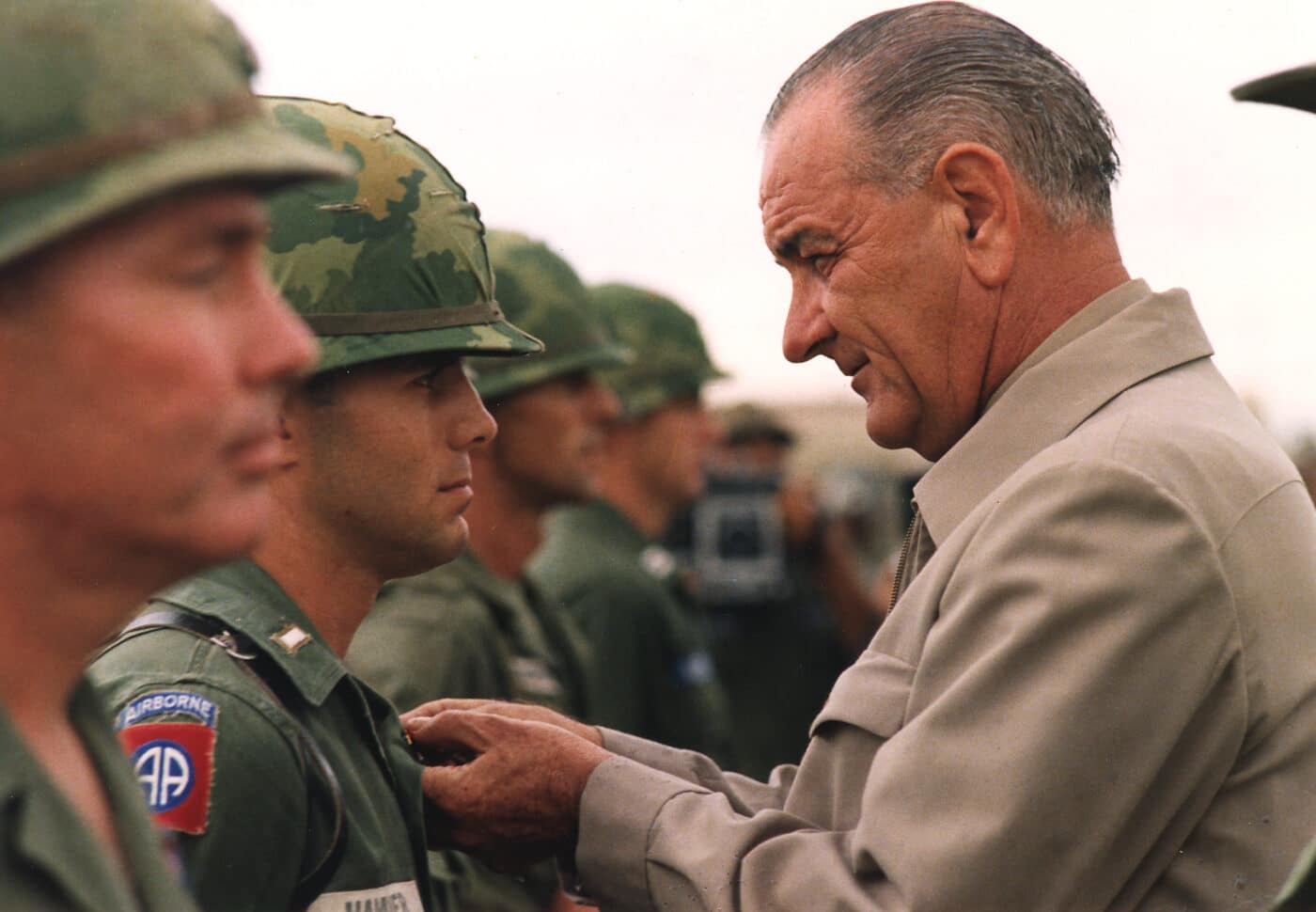 president lyndon johnson decorates a us soldier wearing an m1 helmet with mitchell camo