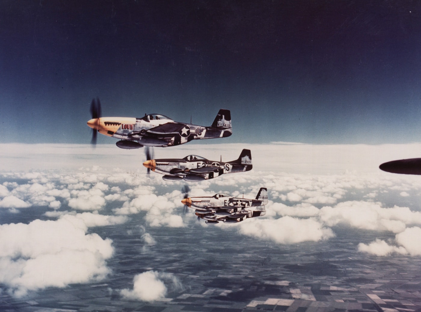 flight of p-51 mustangs escorting a us bomber