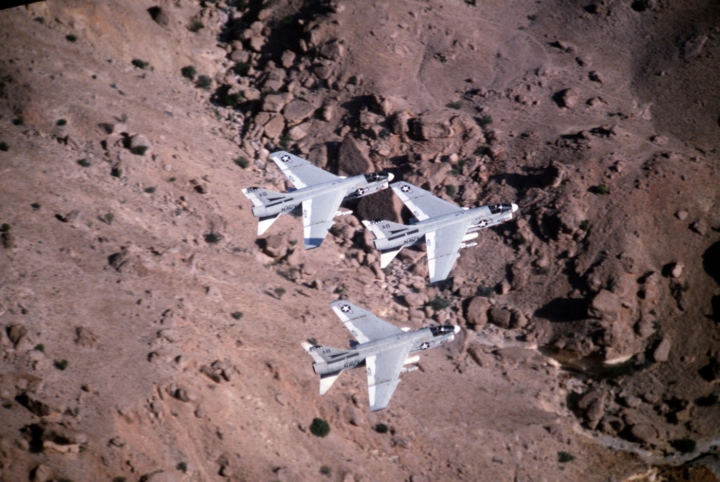 three a-7 corsairs fly over desert from uss america