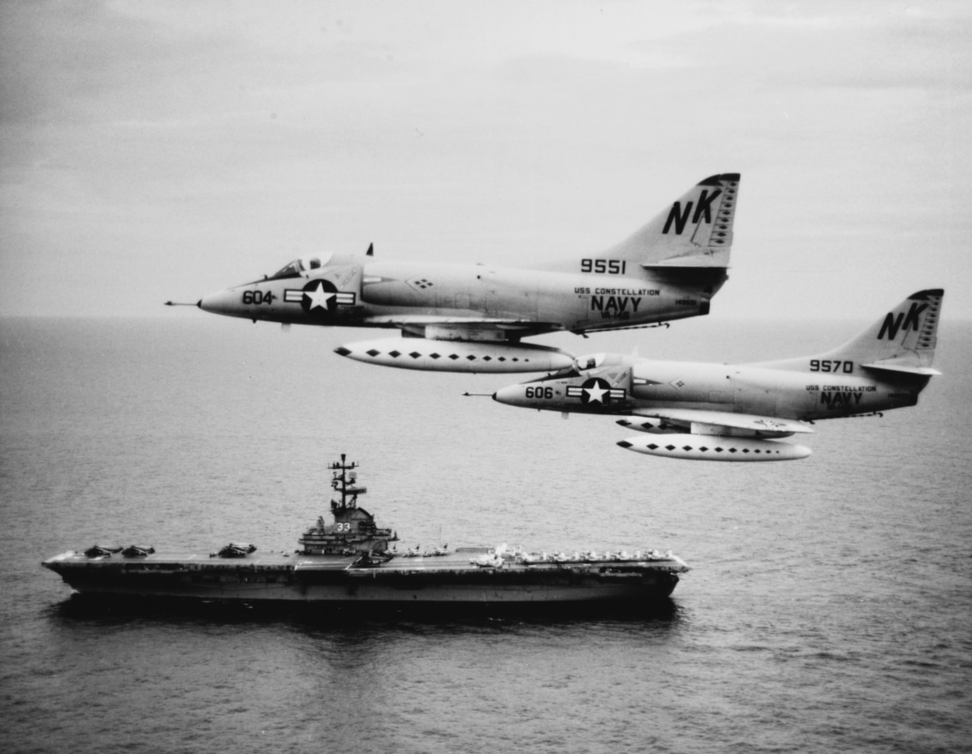 Two A-4C Skyhawk aircraft, of Attack Squadron 146 (VA-146) Fly past USS Kearsarge (CVS-33), 12 August 1964. These planes, from USS Constellation (CVA-64), are Bureau #s 149551 and 149570. Official U.S. Navy Photograph.