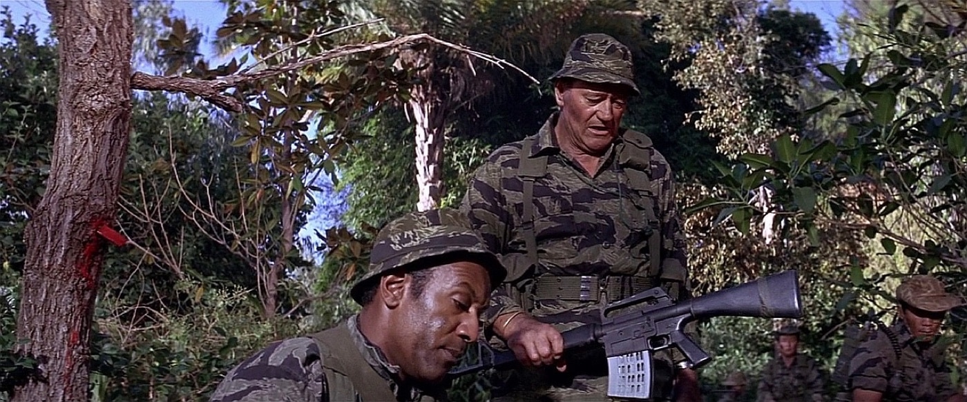 Screenshot from the movie The Green Berets showing John Wayne holding the Mattel Marauder that he is about to smash against a tree.