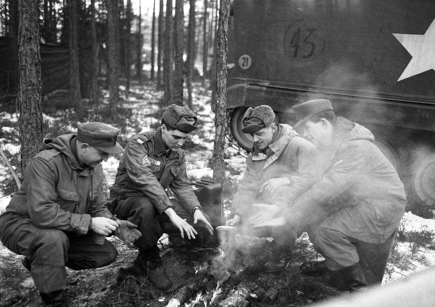 sgt elvis presley warming at campfire with other us army soldiers next to m59 apc in west germany