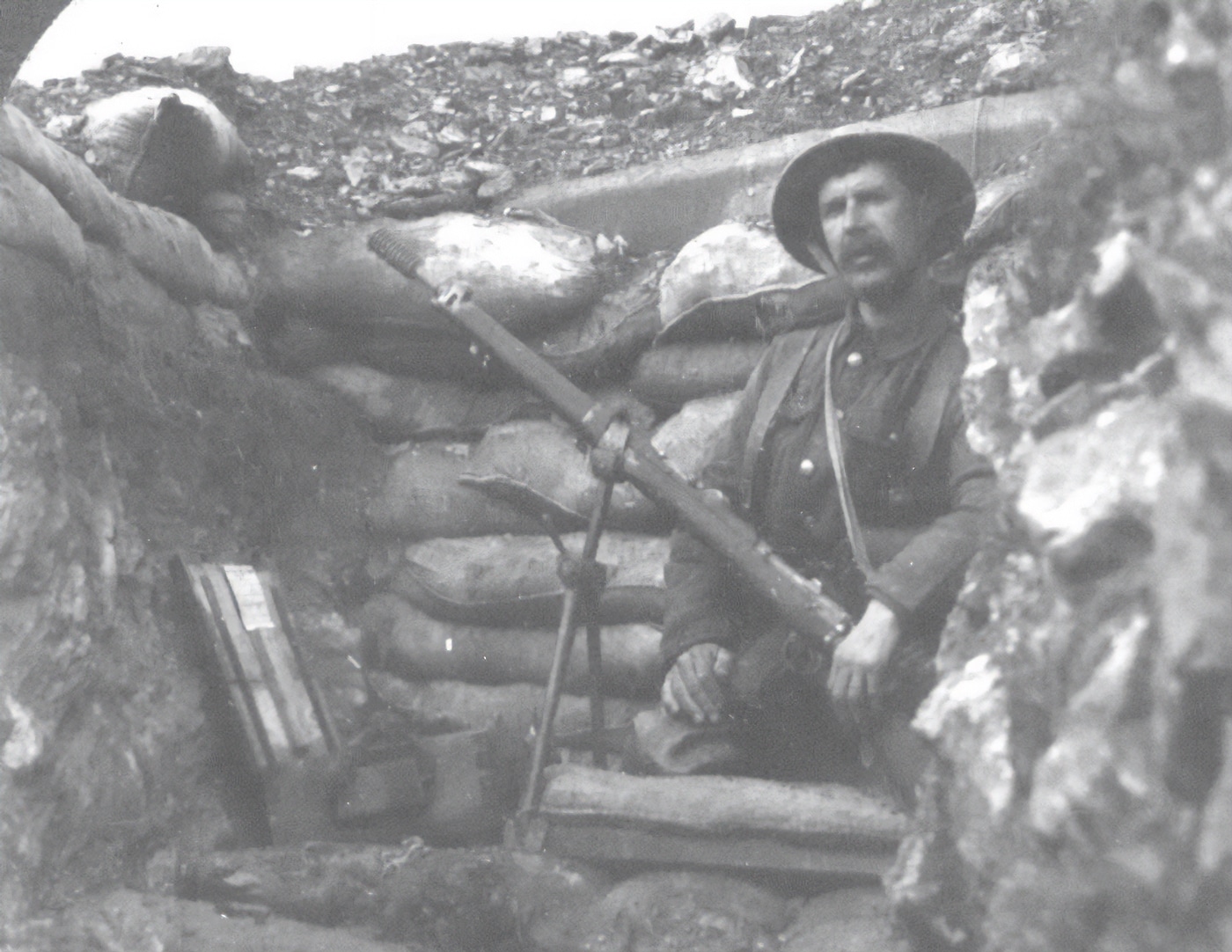 Shown in this rare photograph is a Hales rifle grenade No. 3 in the hands of a British soldier. The soldier is in a front line trench somewhere in the Balkans during World War I. A wooden case of additional grenades is in front of him. His rifle is on a bipod which was specific to the launcher.